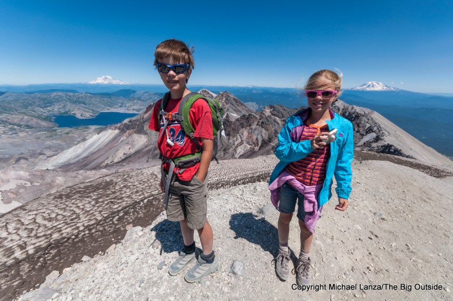 Un adolescente y una chica interpoladora de pie en el borde del cráter del Monte St. Helens, Washington.