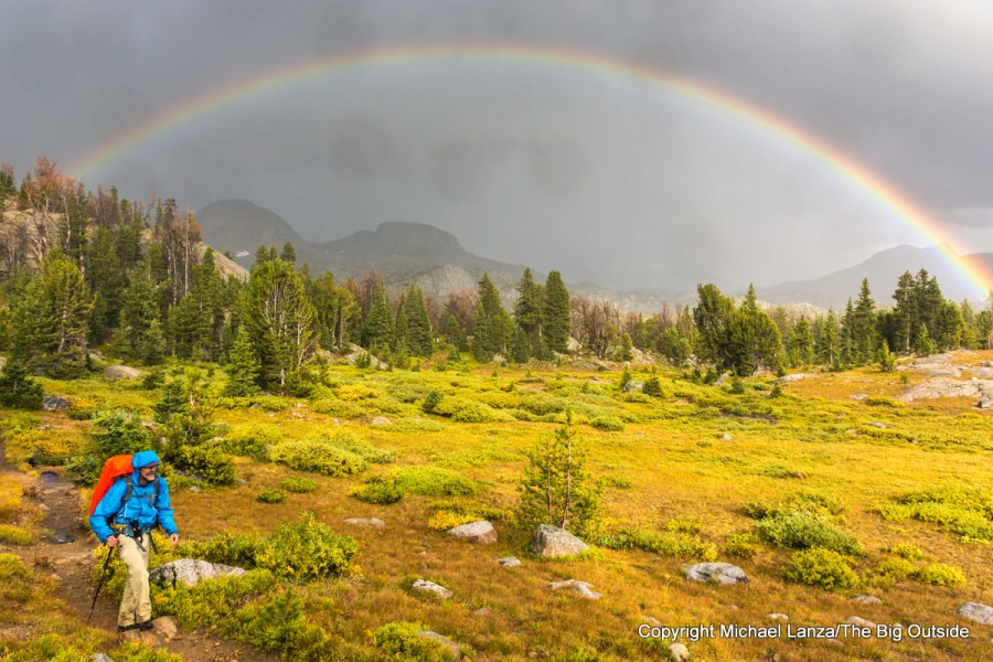 De mochilero bajo la lluvia, bajo un arcoíris, en Wind River Range en Wyoming.
