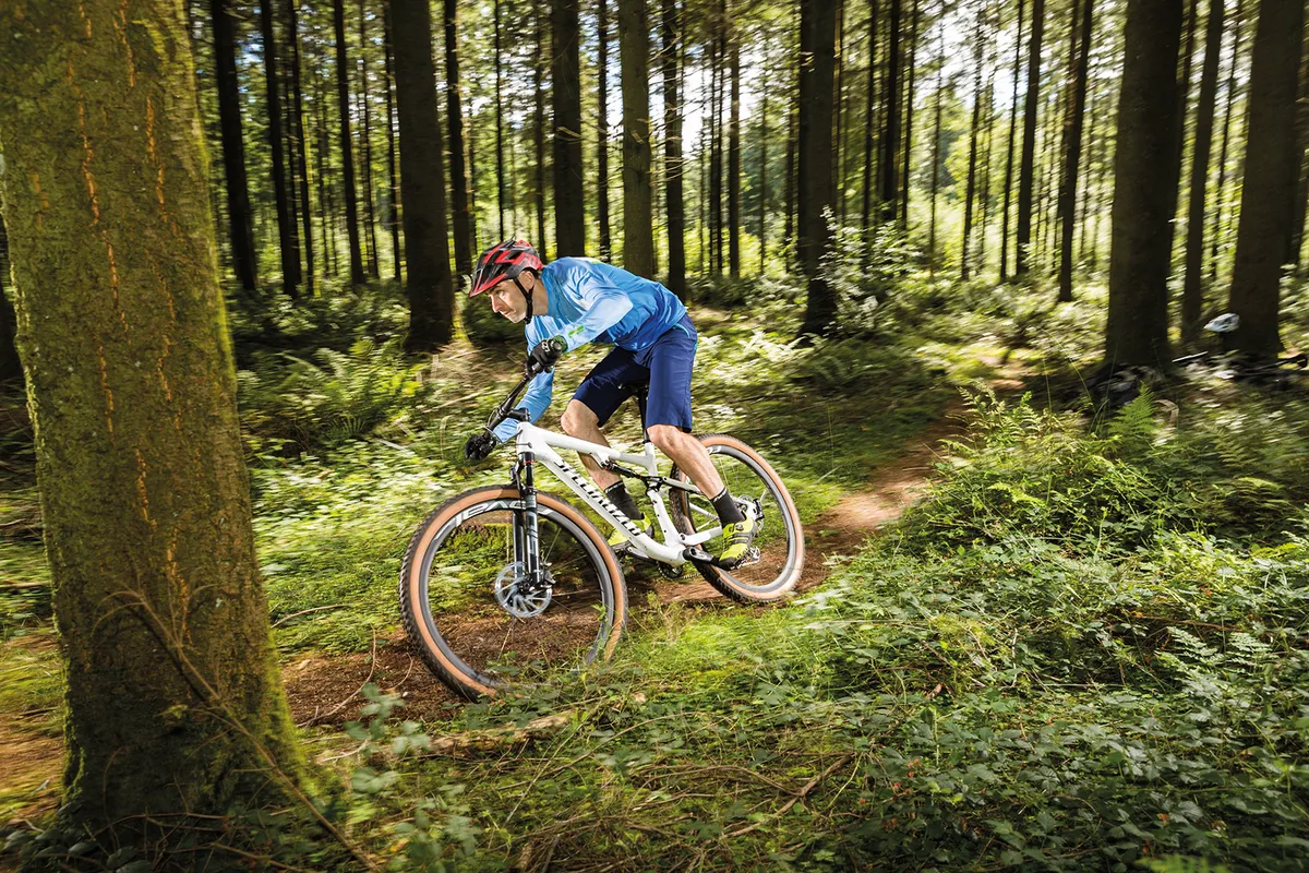 Profesional épico especializado Ciclista con camiseta azul montando la bicicleta de montaña de doble suspensión Specialized Epic Pro