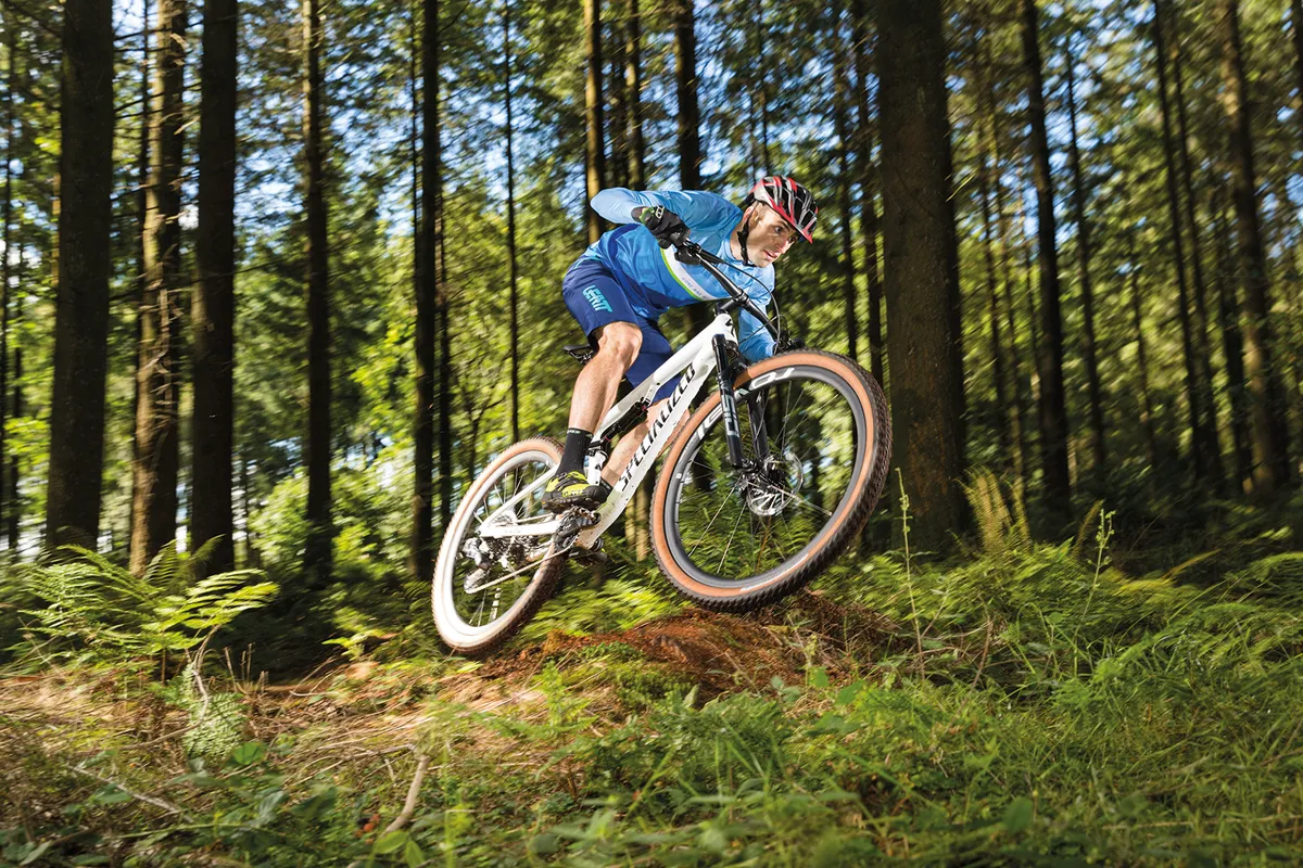 Profesional épico especializado Ciclista con camiseta azul montando la bicicleta de montaña de doble suspensión Specialized Epic Pro