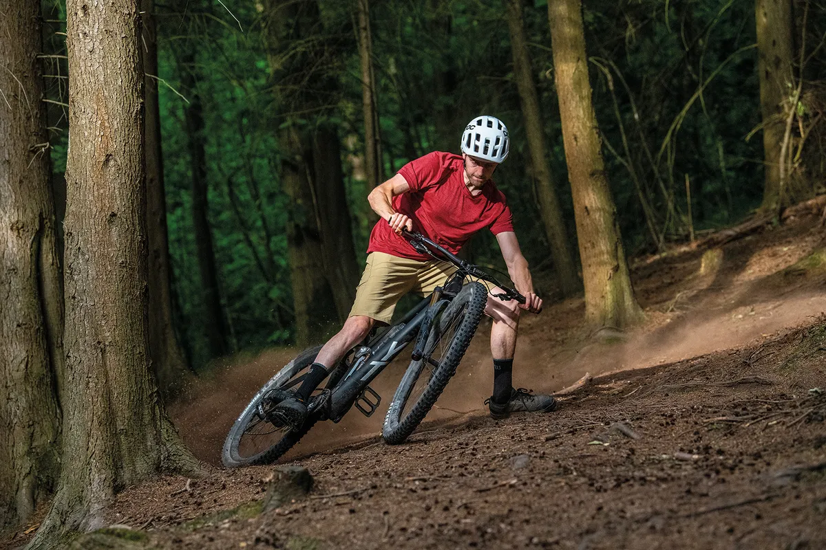 Carrera YT Izzo Pro Ciclista con top rojo montando la bicicleta de montaña de suspensión total YT Izzo Pro Race