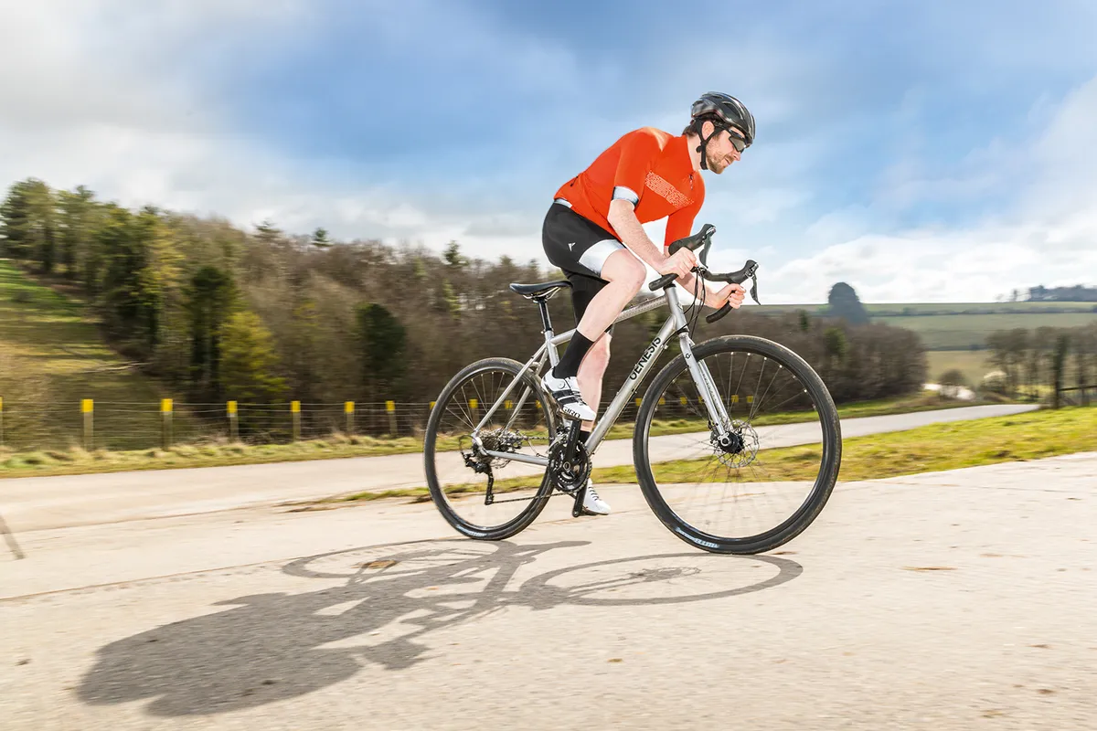 GƩnesis CDA Ciclista masculino con camiseta roja montando la bicicleta de carretera Genesis CDA